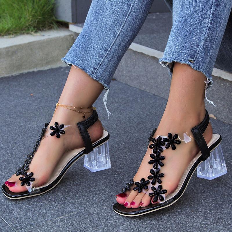 Woman wearing fashion flower sandals with transparent square heels, styled with casual jeans for summer.